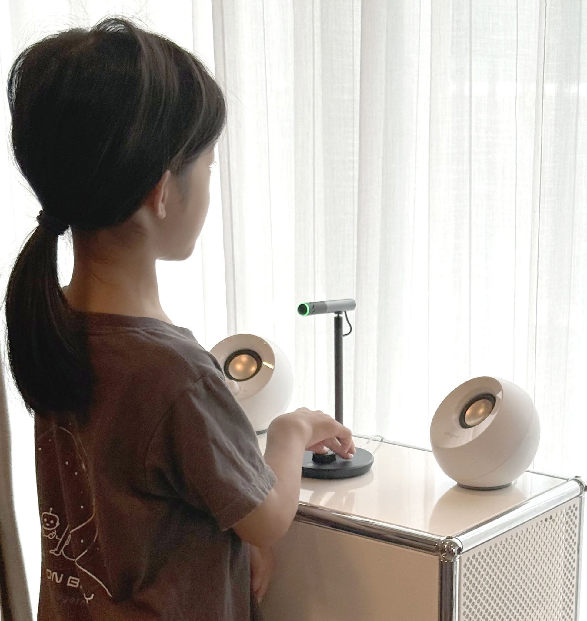 A child talking with an AI by pressing a push-to-talk microphone — a new screenless medium that doesn't take over the child's field of view